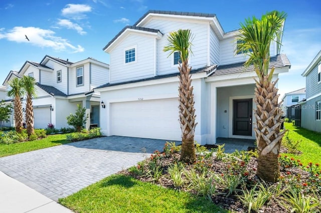 view of front of home featuring decorative driveway, an attached garage, and stucco siding