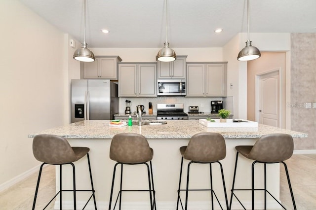 kitchen featuring hanging light fixtures, a breakfast bar, an island with sink, and stainless steel appliances