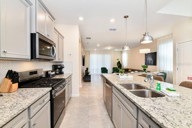 kitchen with tasteful backsplash, light tile patterned floors, stainless steel appliances, hanging light fixtures, and sink