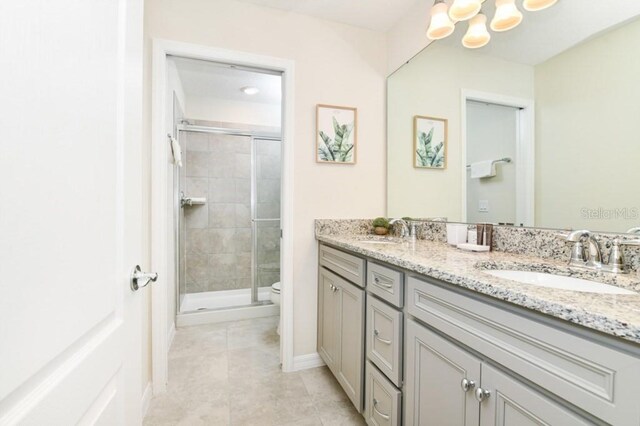 bathroom with toilet, tile patterned floors, double sink vanity, and walk in shower