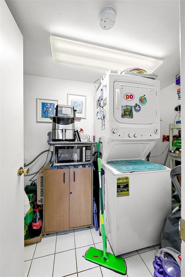 clothes washing area with stacked washer / drying machine and light tile patterned floors