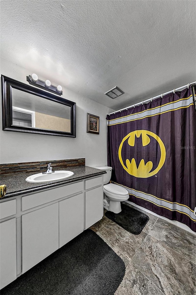 bathroom featuring vanity, toilet, a shower with shower curtain, and a textured ceiling