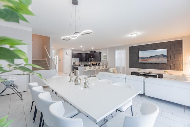 kitchen featuring stainless steel appliances, dark brown cabinets, pendant lighting, light tile patterned floors, and a center island