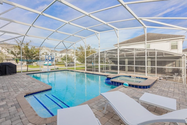 view of pool with an in ground hot tub, glass enclosure, and a patio area