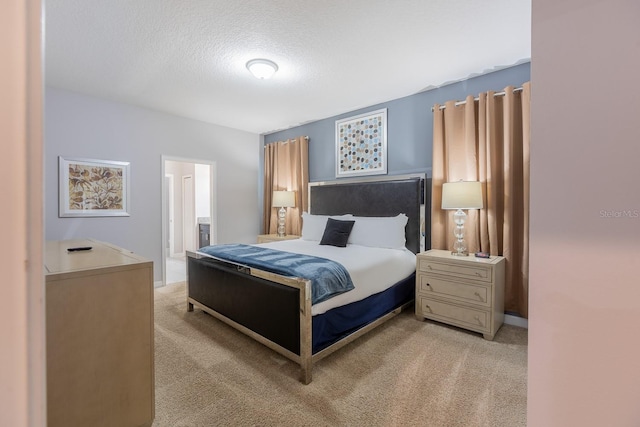 bedroom with ensuite bath, light carpet, and a textured ceiling