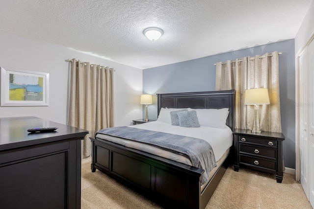 bedroom featuring light carpet, a closet, and a textured ceiling