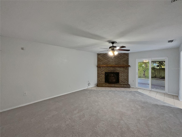 unfurnished living room featuring ceiling fan, light colored carpet, a textured ceiling, and a brick fireplace