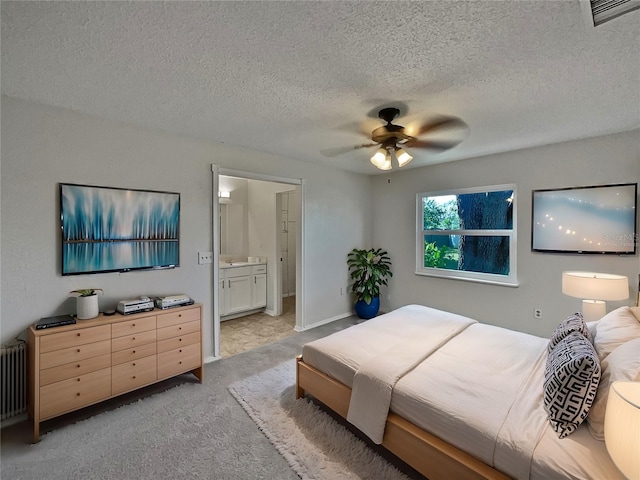 bedroom featuring light carpet, radiator, ensuite bath, and ceiling fan