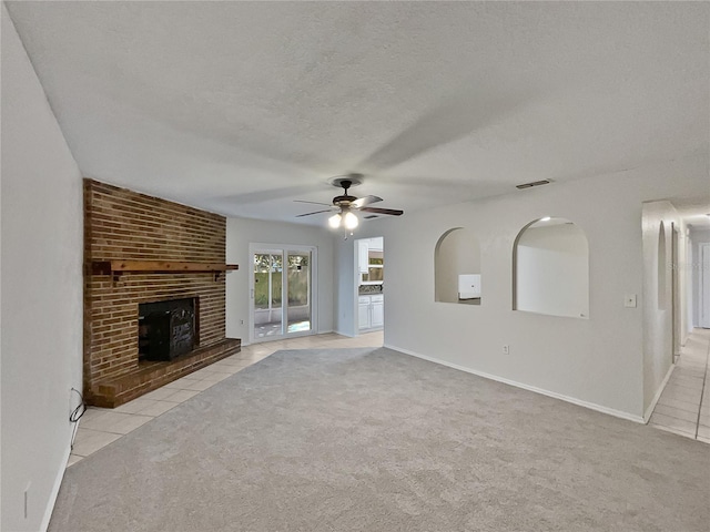 unfurnished living room featuring a fireplace, a textured ceiling, light colored carpet, and ceiling fan