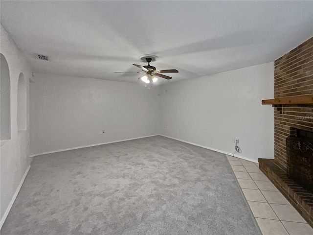 unfurnished living room featuring ceiling fan, light tile patterned flooring, and a brick fireplace