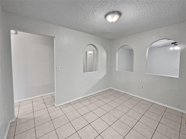 tiled empty room with ceiling fan and a textured ceiling