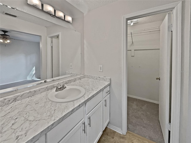 bathroom featuring ceiling fan, vanity, and a textured ceiling