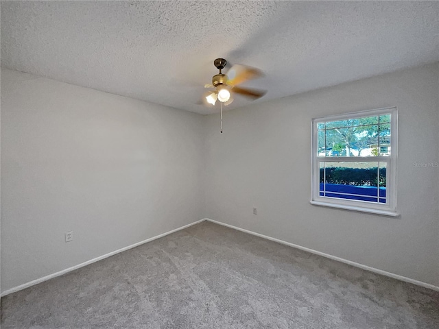 spare room with a textured ceiling, carpet floors, and ceiling fan