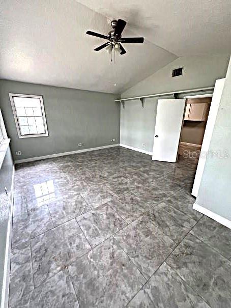 unfurnished bedroom with a closet, tile patterned floors, ceiling fan, vaulted ceiling, and a textured ceiling