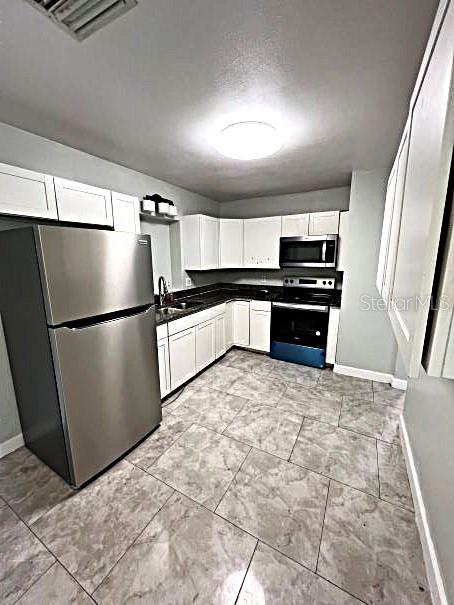 kitchen featuring white cabinets, sink, appliances with stainless steel finishes, and light tile patterned floors