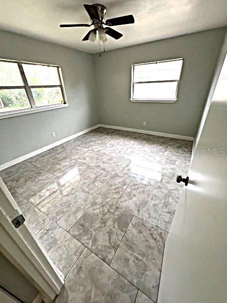 tiled spare room with ceiling fan