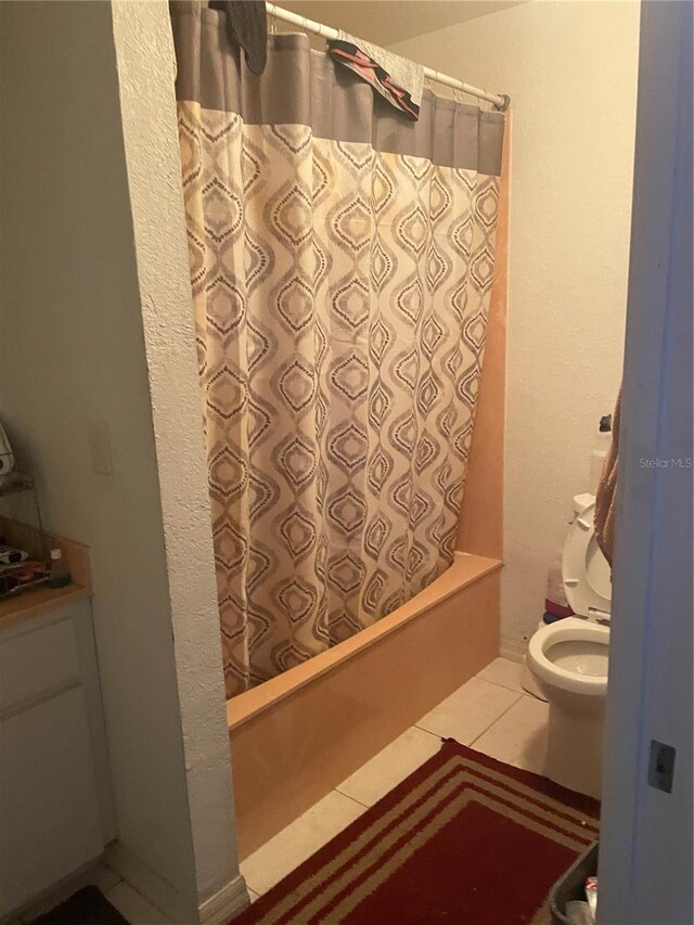 full bathroom featuring shower / bath combination with curtain, tile patterned flooring, and toilet