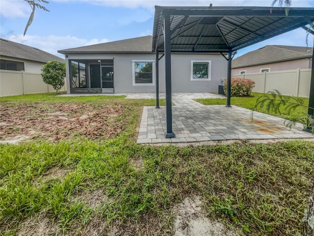 back of property with a patio, a gazebo, a yard, and a sunroom