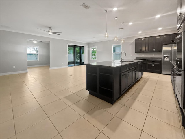 kitchen with stainless steel fridge, decorative light fixtures, sink, ornamental molding, and a center island with sink