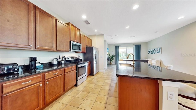 kitchen with light tile patterned floors, an island with sink, stainless steel appliances, a breakfast bar, and sink