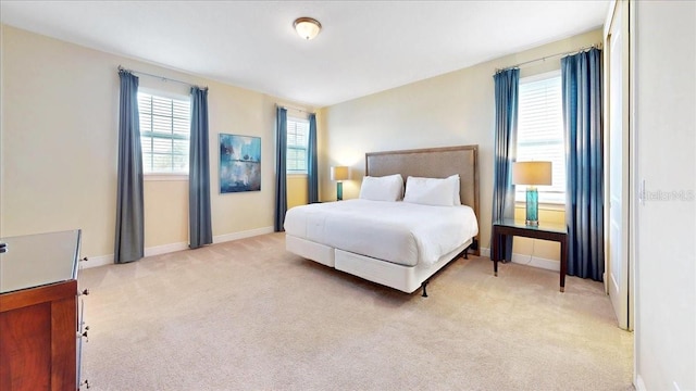 bedroom featuring light colored carpet and multiple windows