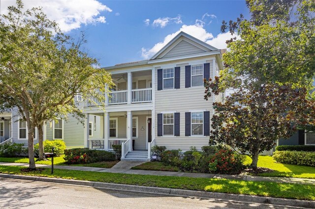 greek revival inspired property with a balcony, a porch, and a front yard