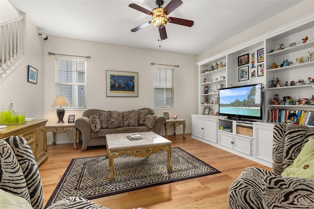 living room featuring ceiling fan, a textured ceiling, and light wood-type flooring