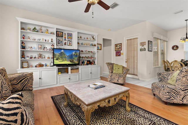 living room with ceiling fan with notable chandelier and light wood-type flooring