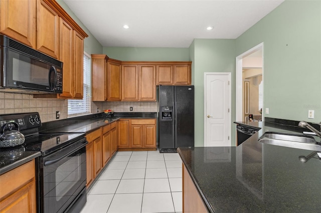 kitchen with sink, tasteful backsplash, light tile patterned floors, dark stone counters, and black appliances