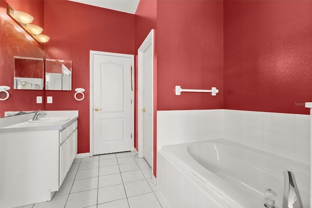 bathroom featuring a relaxing tiled tub, vanity, and tile patterned flooring