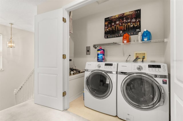 laundry room featuring an inviting chandelier and washer and clothes dryer