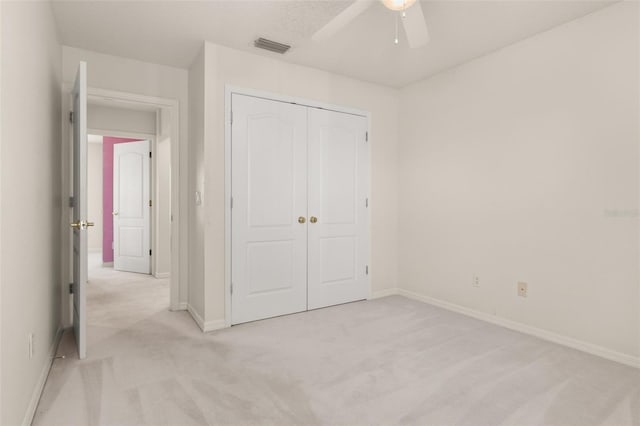 unfurnished bedroom featuring light carpet, a closet, and ceiling fan