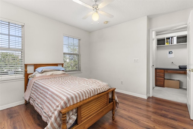 bedroom with dark hardwood / wood-style floors, built in desk, a textured ceiling, and ceiling fan