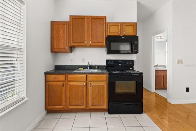 kitchen featuring sink, light tile patterned floors, and black appliances