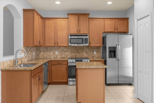 kitchen featuring stainless steel appliances, sink, light tile patterned floors, and light stone counters