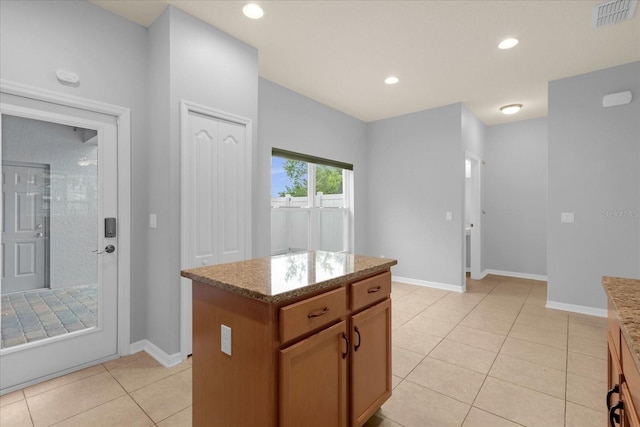 kitchen featuring light tile patterned flooring, light stone counters, and a kitchen island