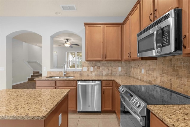 kitchen featuring light tile patterned flooring, sink, tasteful backsplash, stainless steel appliances, and light stone countertops