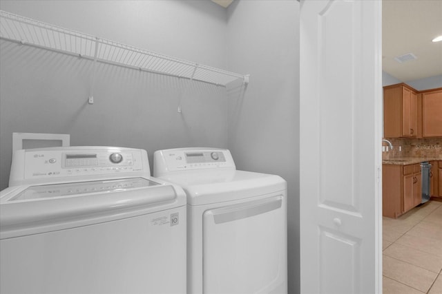 clothes washing area with light tile patterned floors and washing machine and dryer