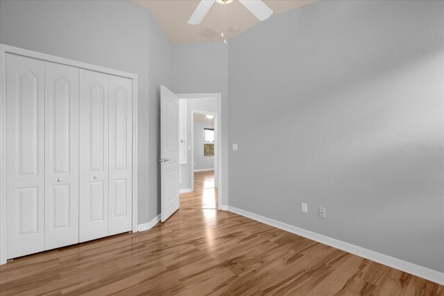 unfurnished bedroom with ceiling fan, lofted ceiling, light hardwood / wood-style floors, and a closet