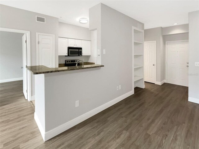 kitchen with kitchen peninsula, white cabinets, dark stone countertops, and appliances with stainless steel finishes