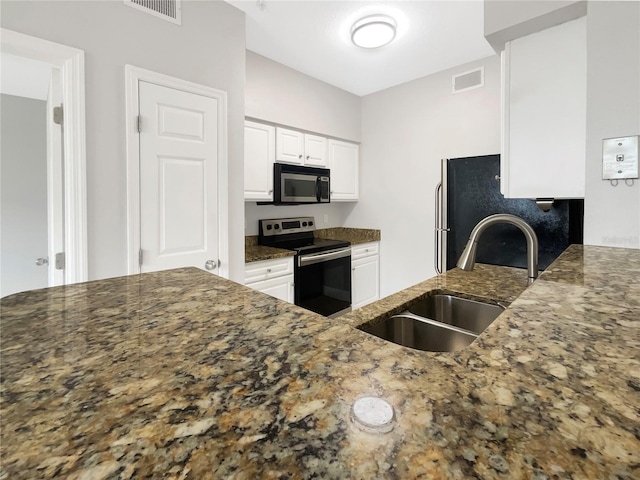 kitchen featuring white cabinets, stainless steel appliances, dark stone counters, and sink