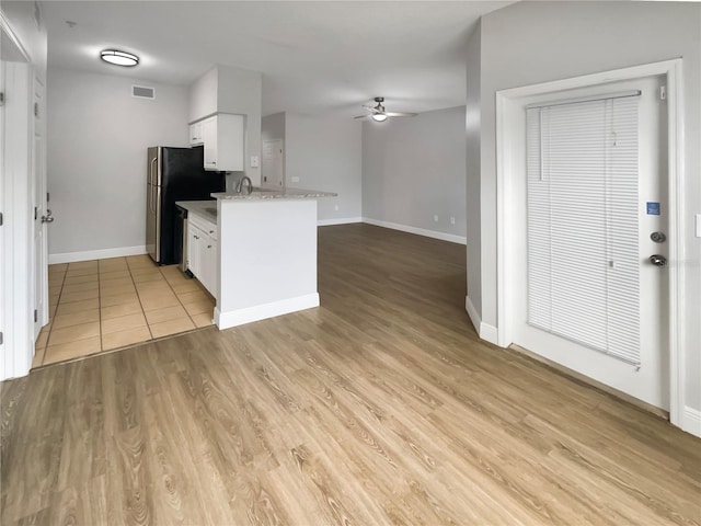 kitchen featuring ceiling fan, white cabinets, light wood-type flooring, light stone counters, and stainless steel refrigerator