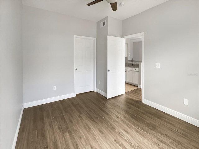 unfurnished bedroom featuring sink, dark wood-type flooring, and ceiling fan