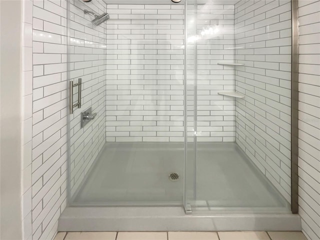 bathroom with a shower with door and tile patterned flooring