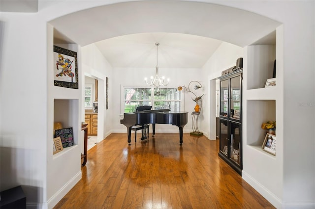 misc room with lofted ceiling, wood-type flooring, and a chandelier