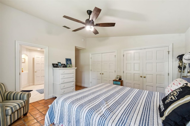 bedroom with ceiling fan, vaulted ceiling, multiple closets, and tile patterned flooring