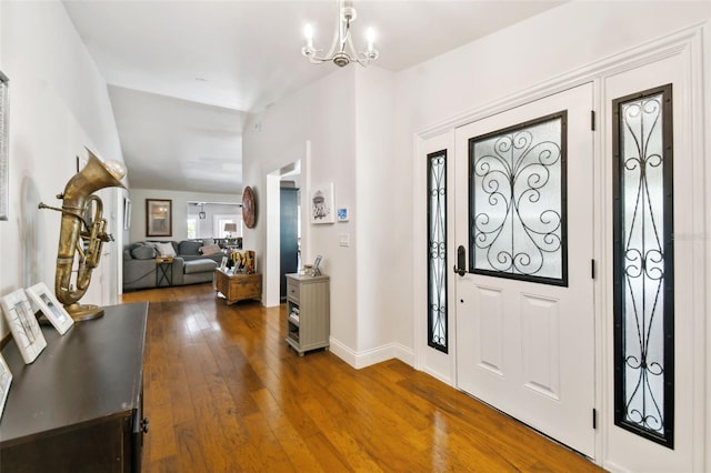 entrance foyer featuring vaulted ceiling, dark hardwood / wood-style flooring, and an inviting chandelier