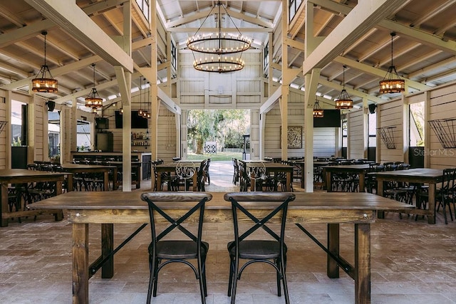 dining room featuring wooden walls, a chandelier, high vaulted ceiling, wooden ceiling, and beam ceiling