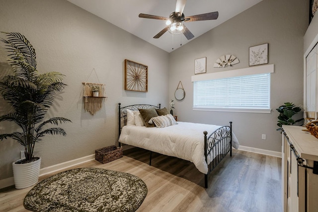 bedroom with ceiling fan, vaulted ceiling, and light hardwood / wood-style flooring