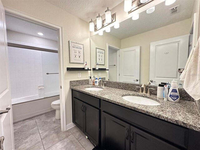 full bathroom featuring tile patterned flooring, a textured ceiling, double vanity, toilet, and tiled shower / bath combo